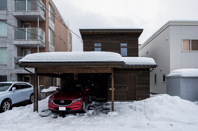 建物との一体感を大切にした造作カーポートは雪かきの手間を軽減。玄関横には宅配ボックスと外物置も造作されている