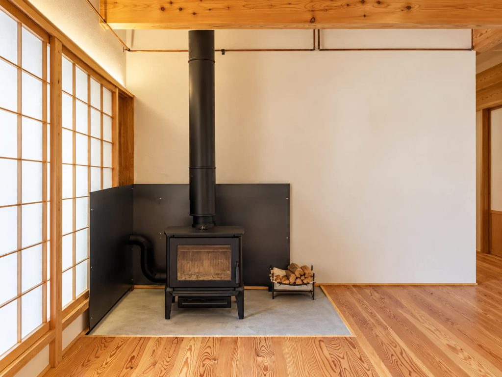 床を一段下げた土間に置いた薪ストーブと不燃の鉄板の壁